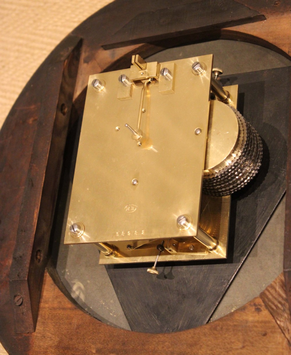 An antique circular wall clock featuring a turned dark beech frame, brass bezel, and painted white dial with Roman numerals. View XI