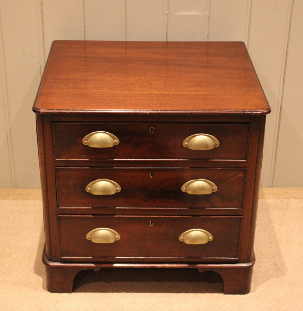 A mid-19th century small low mahogany chest of drawers featuring three graduated drawers with brass cup handles and bracket feet. View II
