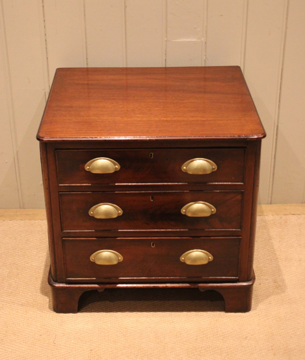 A mid-19th century small low mahogany chest of drawers featuring three graduated drawers with brass cup handles and bracket feet. View IV