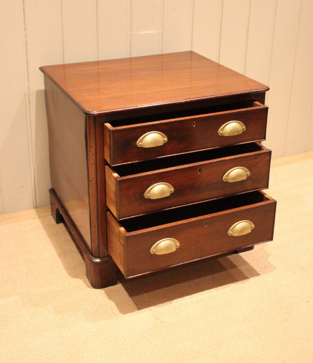 A mid-19th century small low mahogany chest of drawers featuring three graduated drawers with brass cup handles and bracket feet. View VI