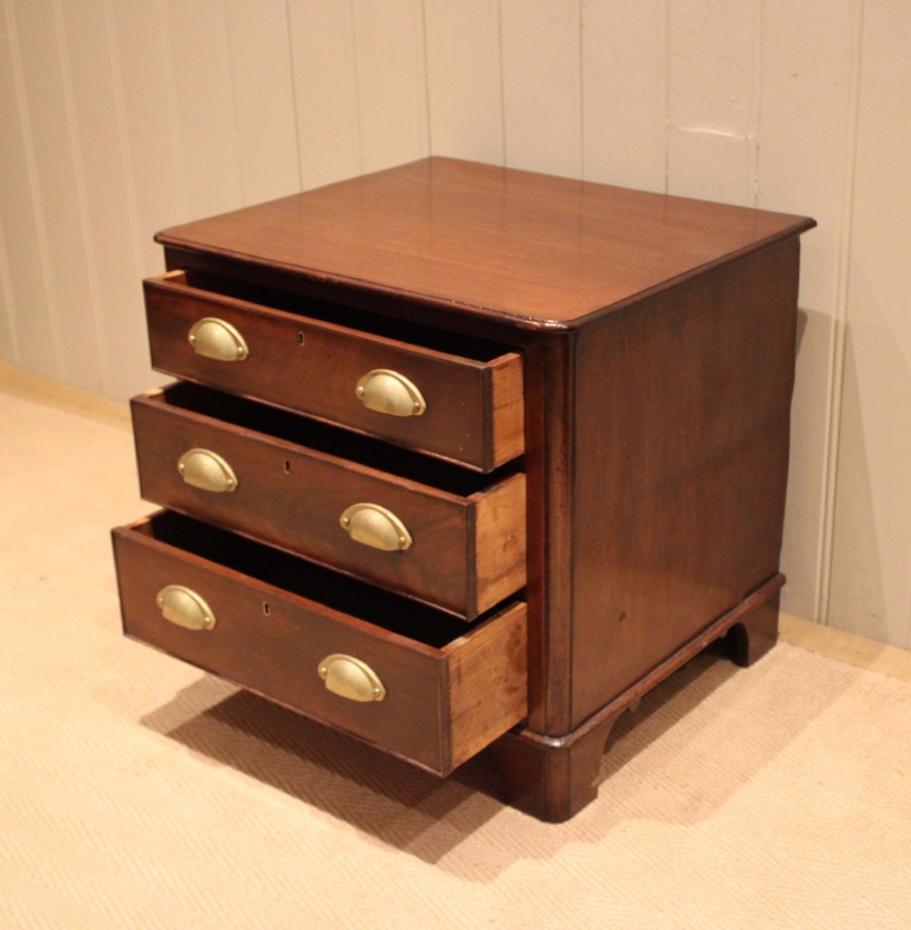 A mid-19th century small low mahogany chest of drawers featuring three graduated drawers with brass cup handles and bracket feet. View VII