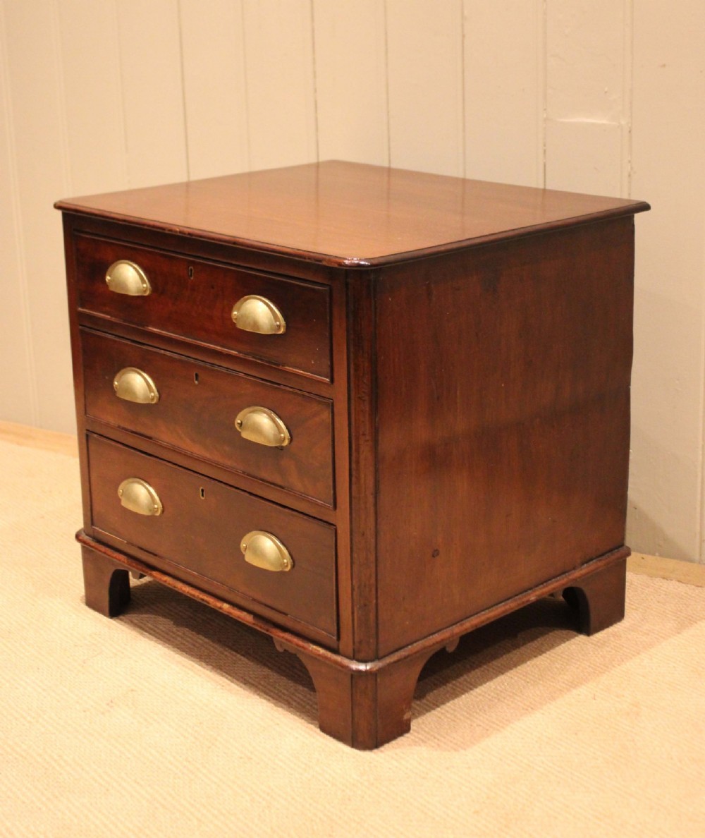 A mid-19th century small low mahogany chest of drawers featuring three graduated drawers with brass cup handles and bracket feet. View VIII