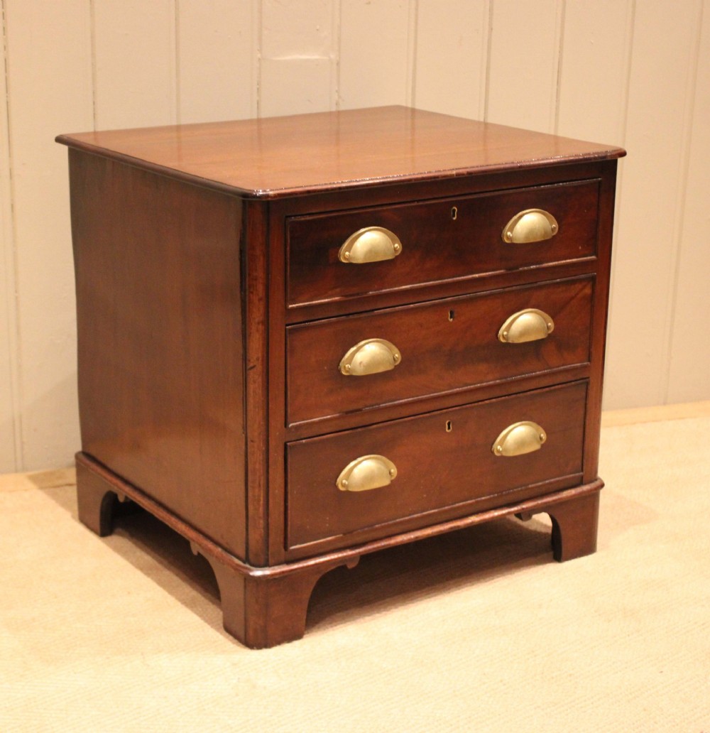 A mid-19th century small low mahogany chest of drawers featuring three graduated drawers with brass cup handles and bracket feet. View X