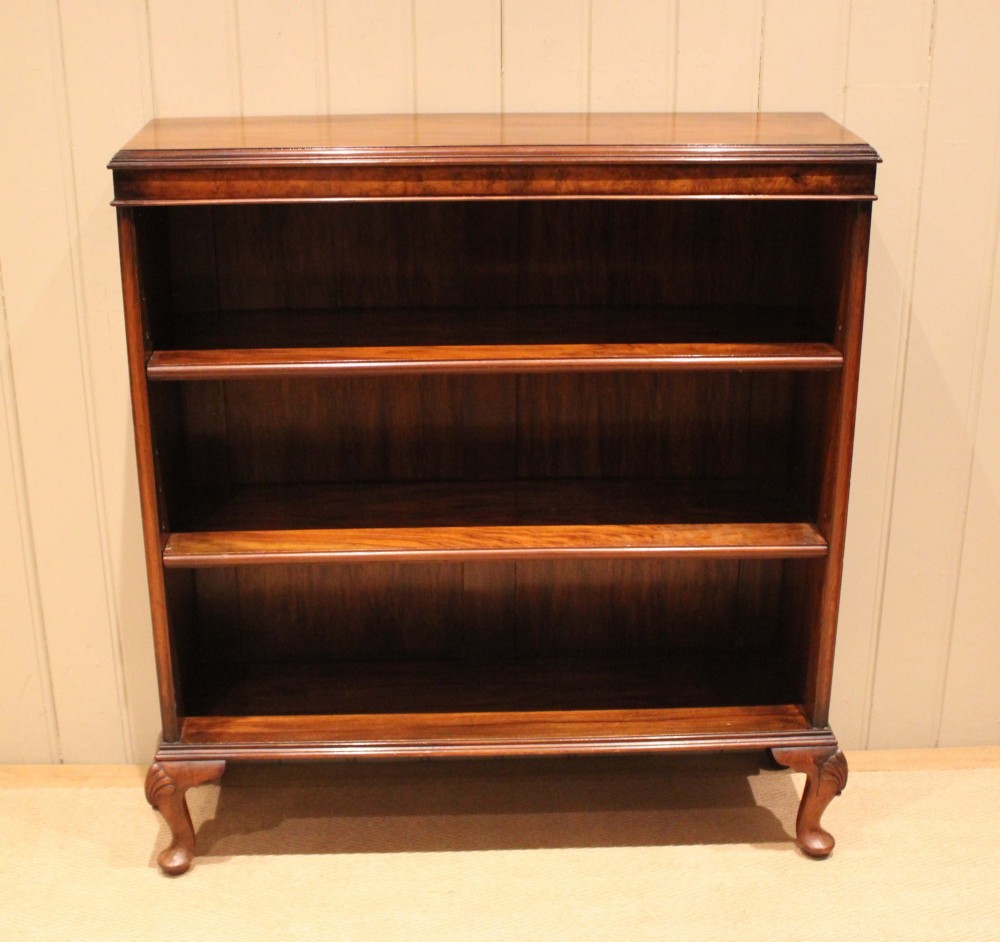 A low antique open walnut bookcase featuring three tiers of books and resting on carved cabriole legs. View II