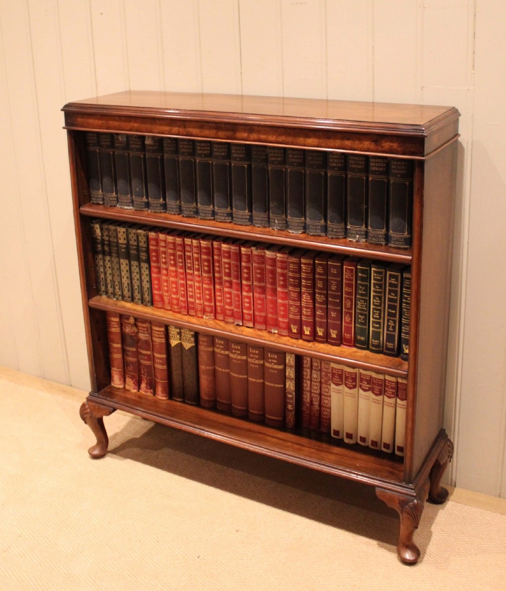 A low antique open walnut bookcase featuring three tiers of books and resting on carved cabriole legs. View III