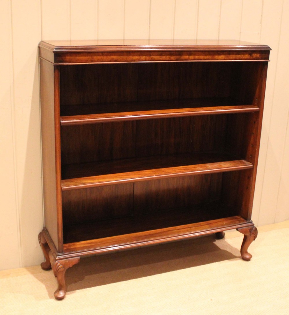 A low antique open walnut bookcase featuring three tiers of books and resting on carved cabriole legs. View IV