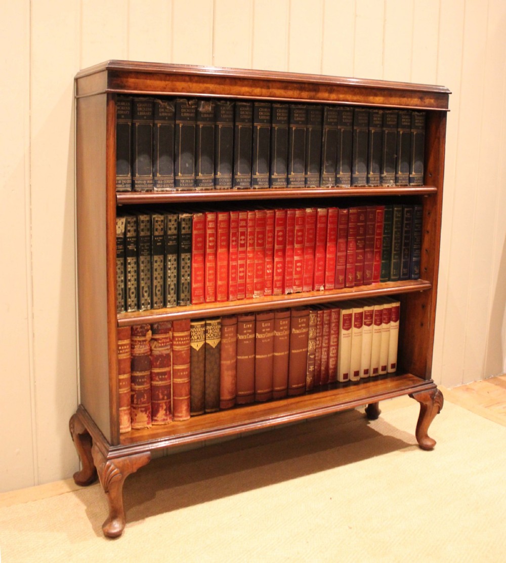 A low antique open walnut bookcase featuring three tiers of books and resting on carved cabriole legs. View V