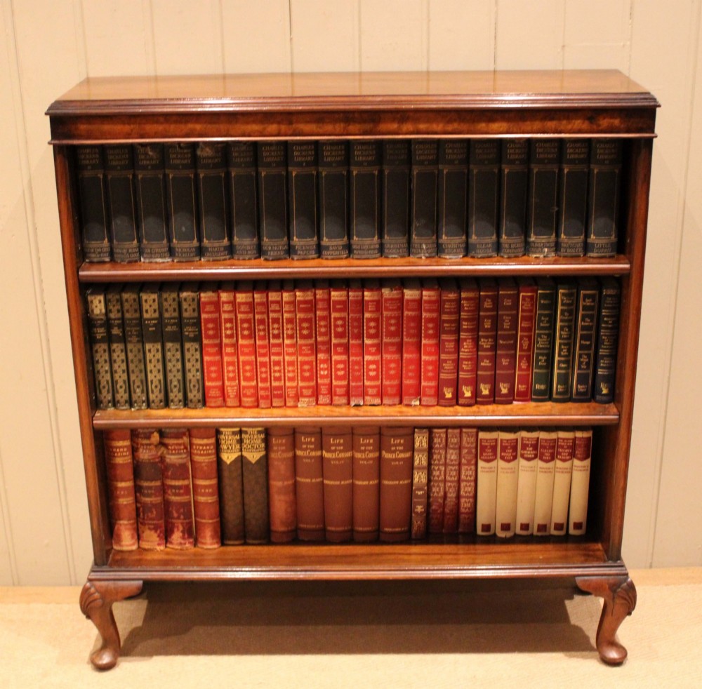 A low antique open walnut bookcase featuring three tiers of books and resting on carved cabriole legs. View VII