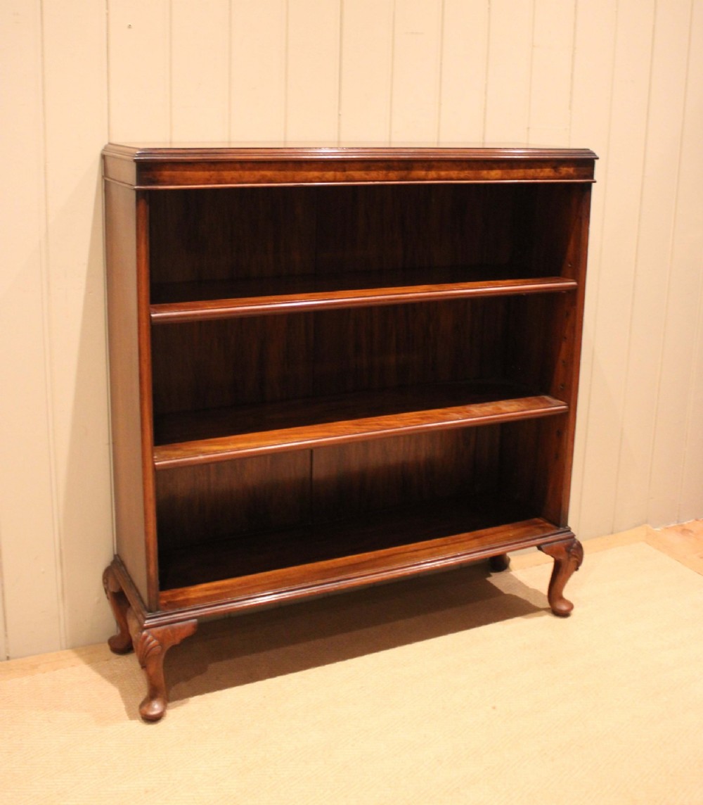 A low antique open walnut bookcase featuring three tiers of books and resting on carved cabriole legs. View VIII
