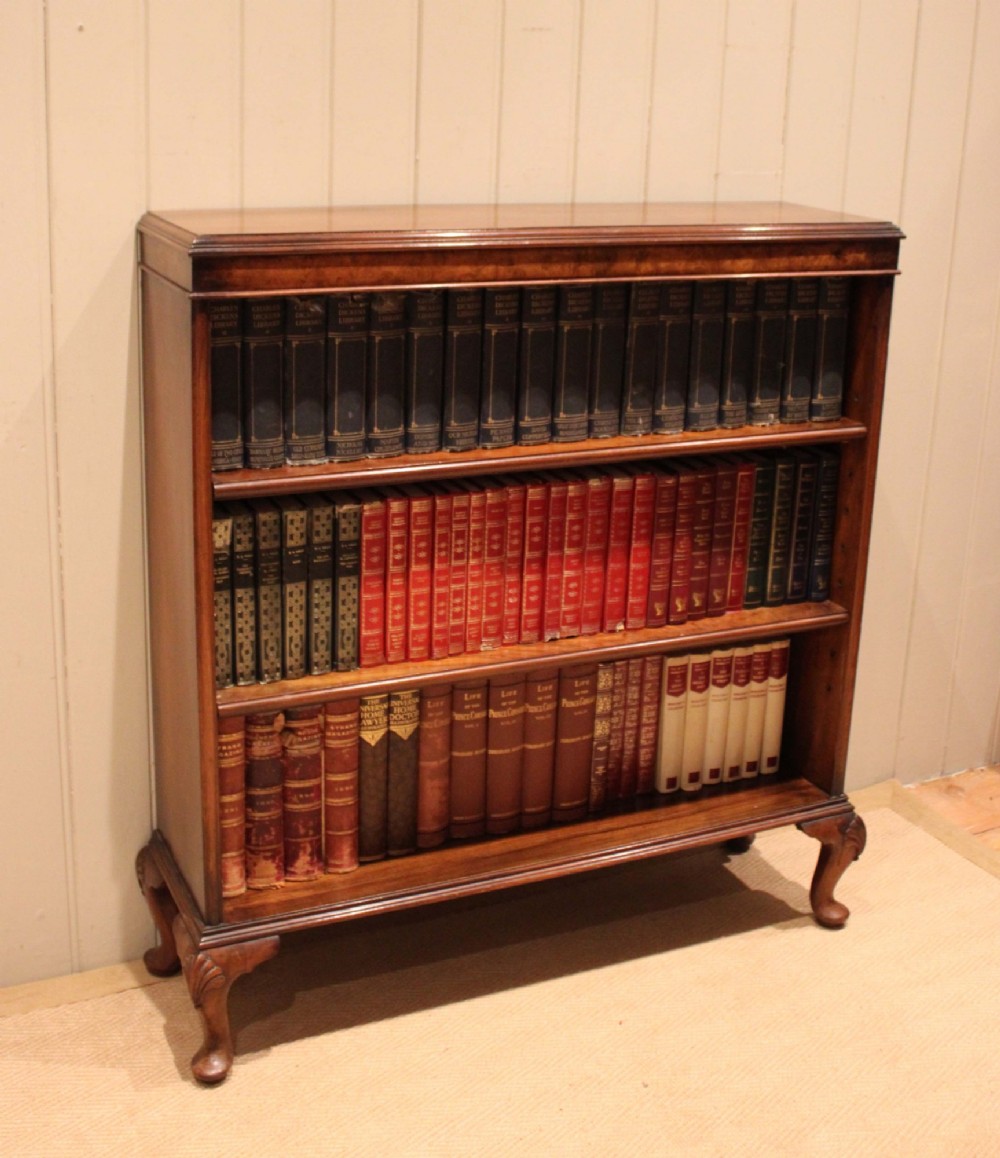 A low antique open walnut bookcase featuring three tiers of books and resting on carved cabriole legs. View IX
