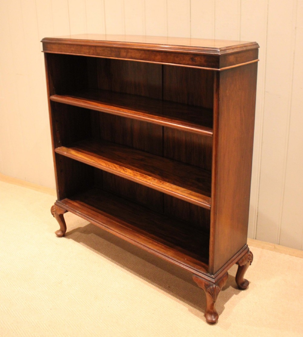 A low antique open walnut bookcase featuring three tiers of books and resting on carved cabriole legs. View XII
