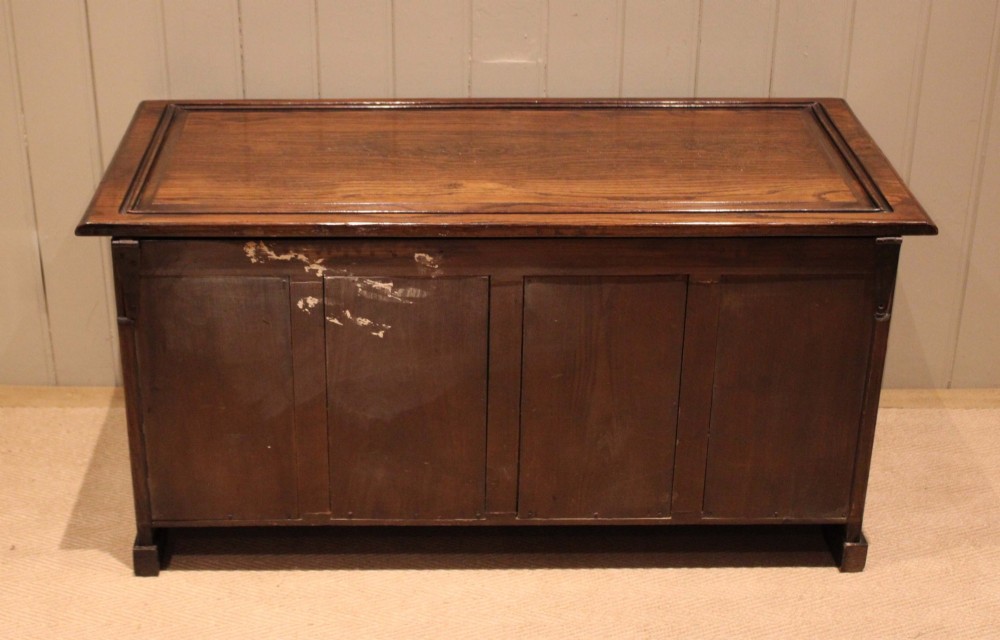 A dark solid oak storage coffer featuring a hinged rectangular lid and four relief-carved front panels. View XII