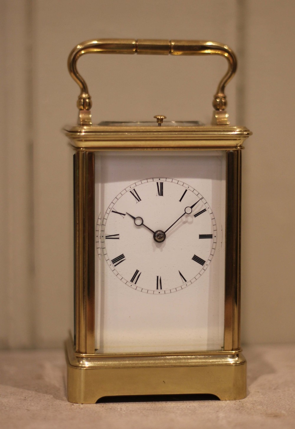A nineteenth-century French polished brass carriage clock featuring bevelled glass side panels, a white enamel dial with Roman numerals, and a hinged top carrying handle. View II