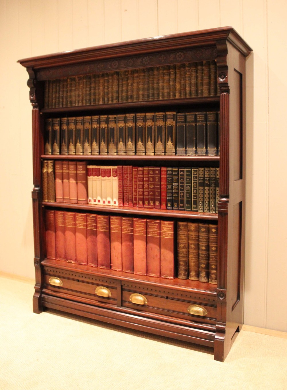 A large late Victorian dark mahogany open bookcase featuring four tiered shelves and two lower drawers with brass cup handles. View III