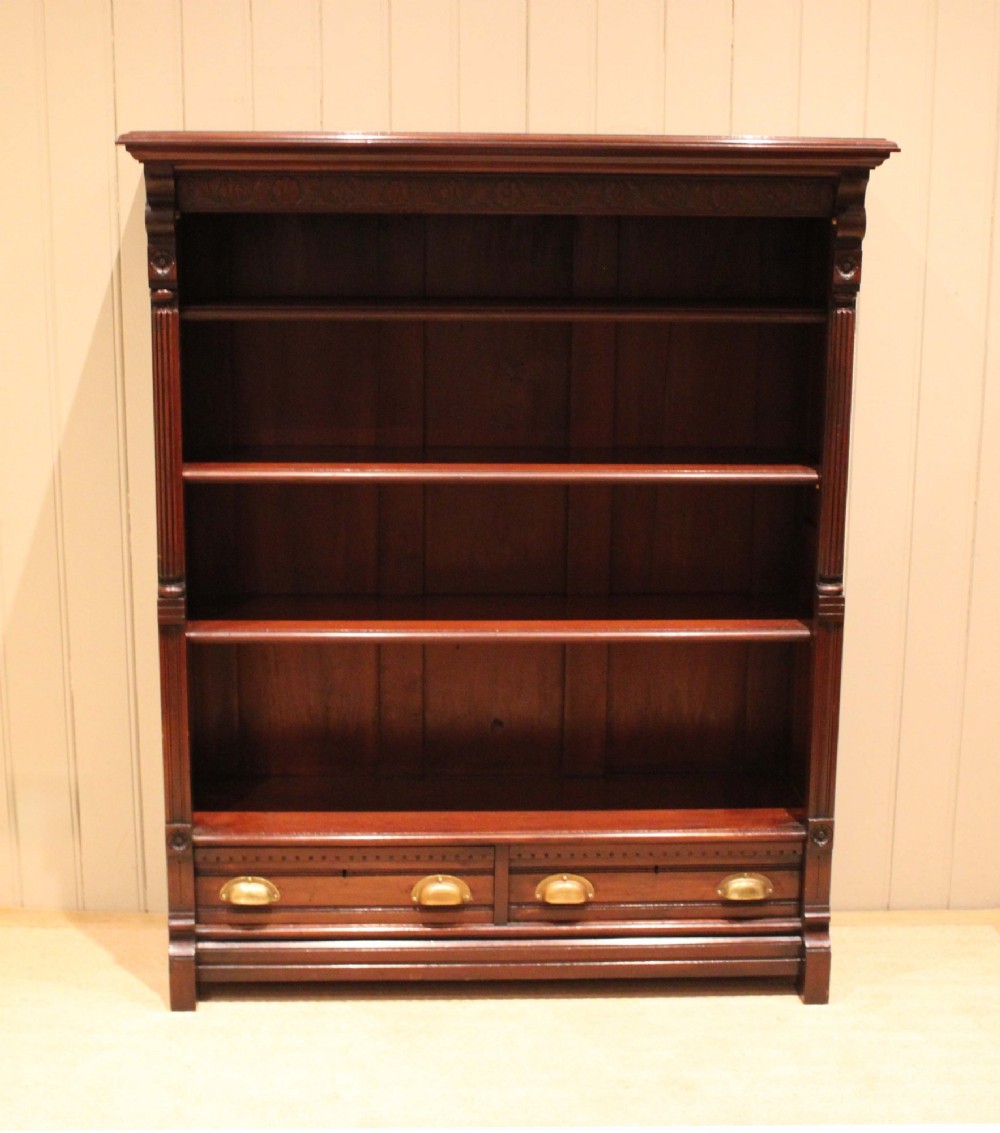 A large late Victorian dark mahogany open bookcase featuring four tiered shelves and two lower drawers with brass cup handles. View IV