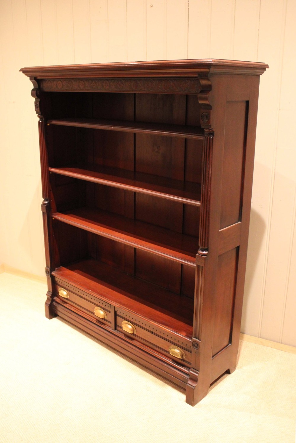 A large late Victorian dark mahogany open bookcase featuring four tiered shelves and two lower drawers with brass cup handles. View VIII