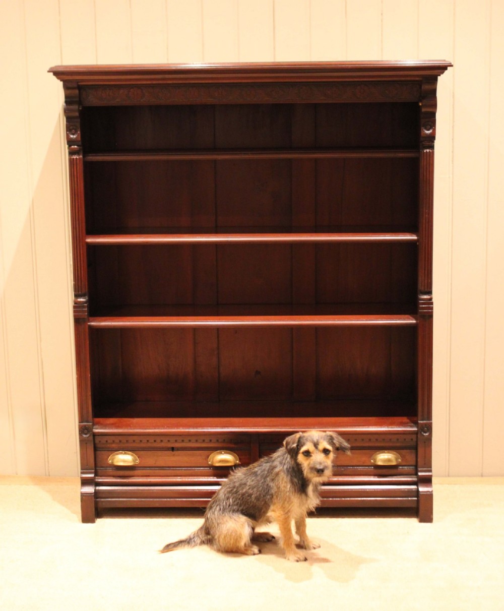 A large late Victorian dark mahogany open bookcase featuring four tiered shelves and two lower drawers with brass cup handles. View X