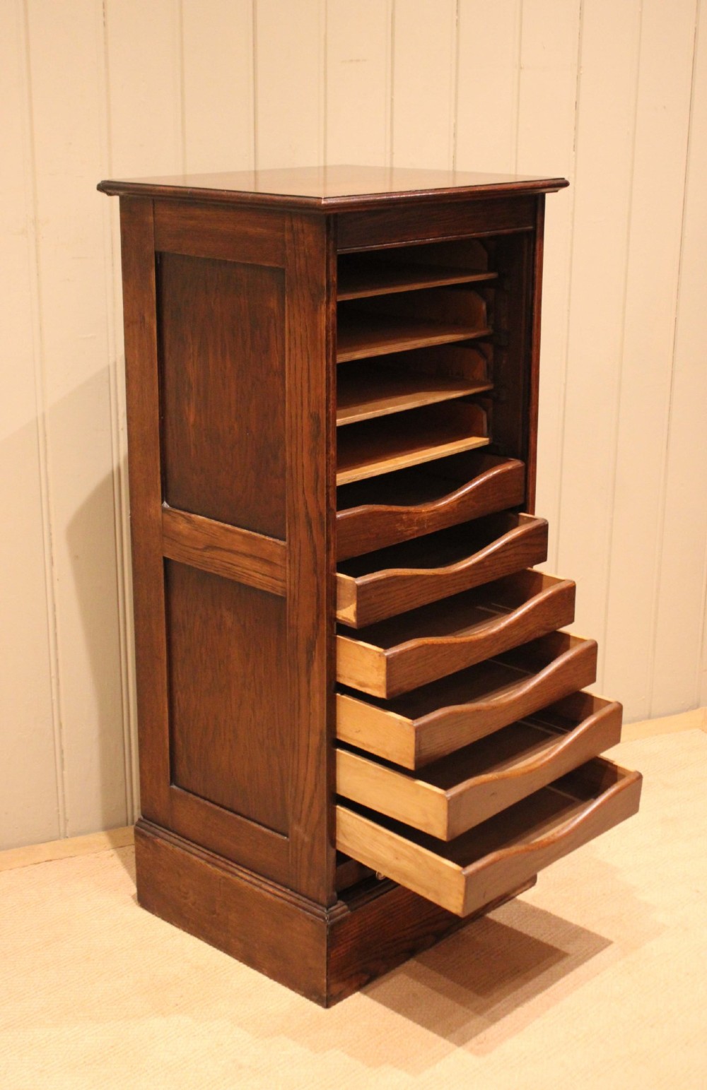 A tall dark oak single-column filing cabinet featuring a slatted wooden tambour front with top brass pull knobs and a keyhole escutcheon. View VIII