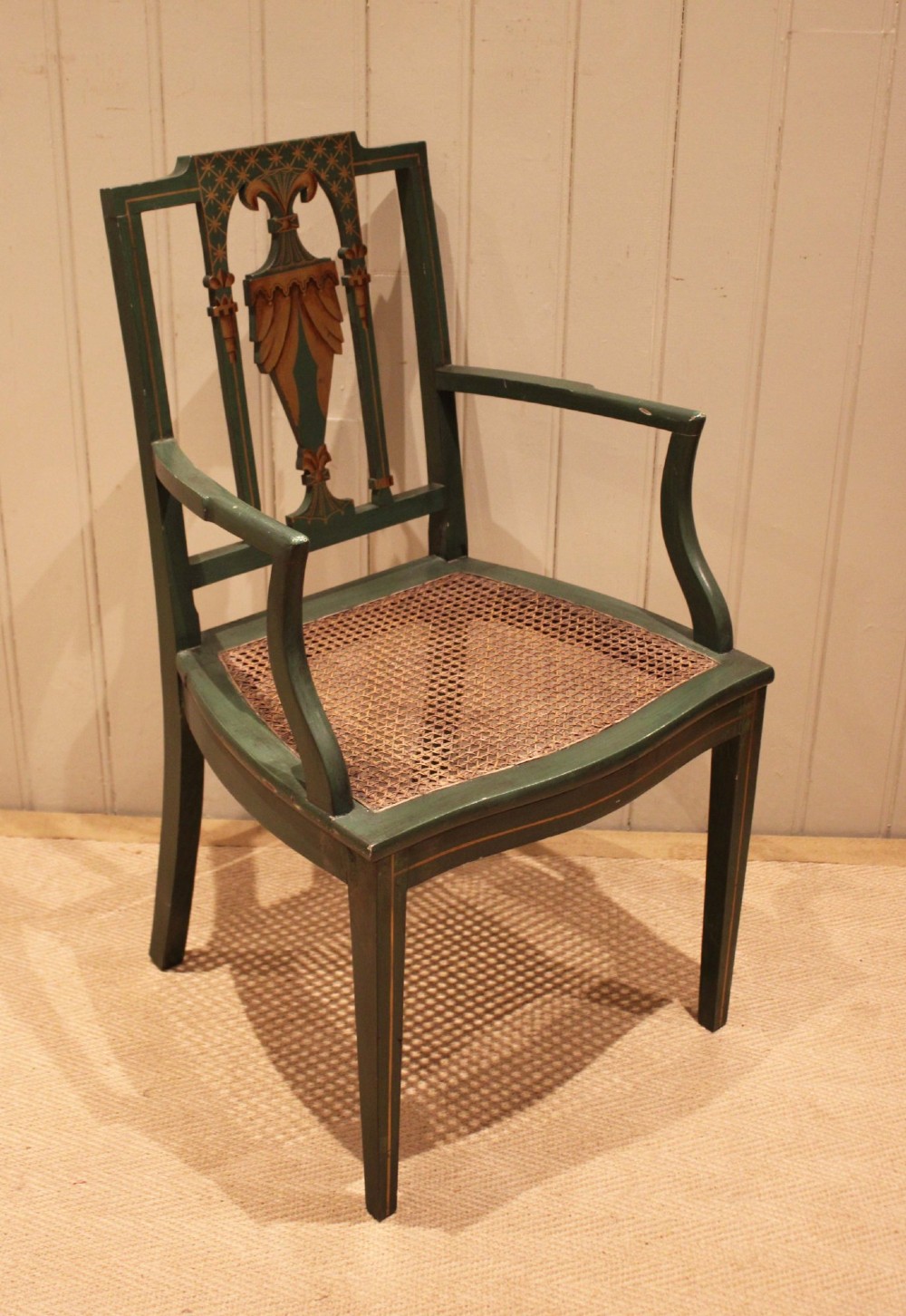 A dark green painted Hepplewhite style armchair featuring a woven cane seat, curved armrests, and hand-painted neoclassical motifs on the backrest. View VIII