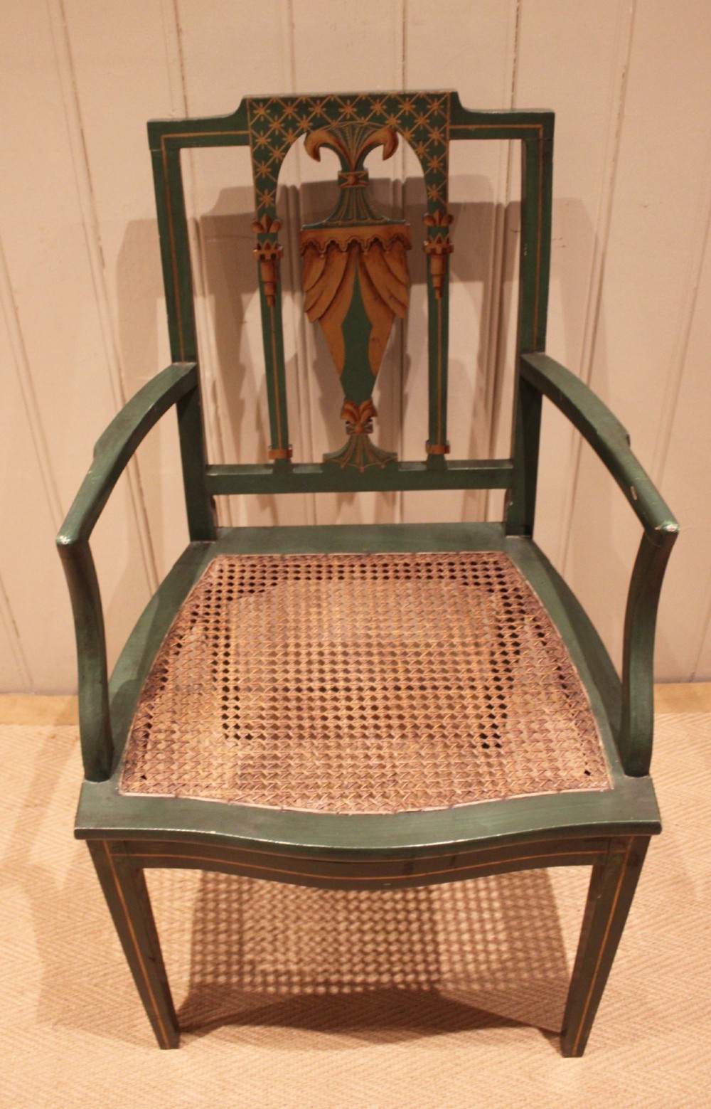 A dark green painted Hepplewhite style armchair featuring a woven cane seat, curved armrests, and hand-painted neoclassical motifs on the backrest. View XI