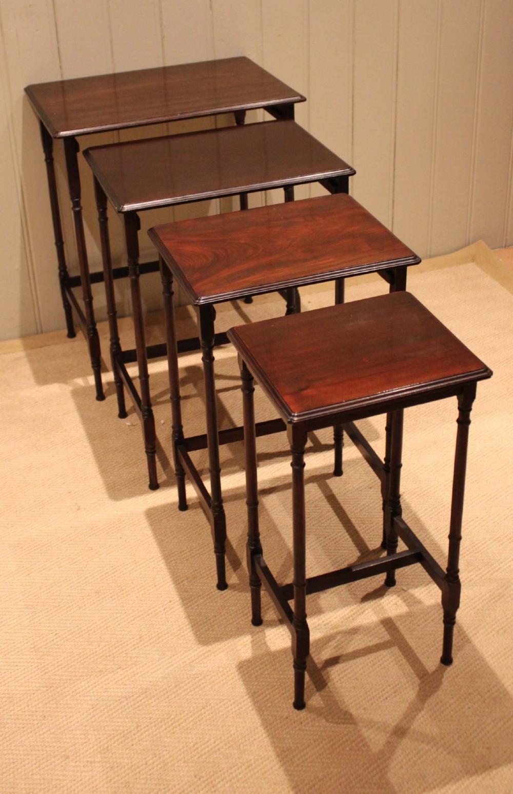 A set of four graduated mahogany nesting tables featuring rectangular tops with moulded edges, slender turned legs, and connecting stretchers. View II