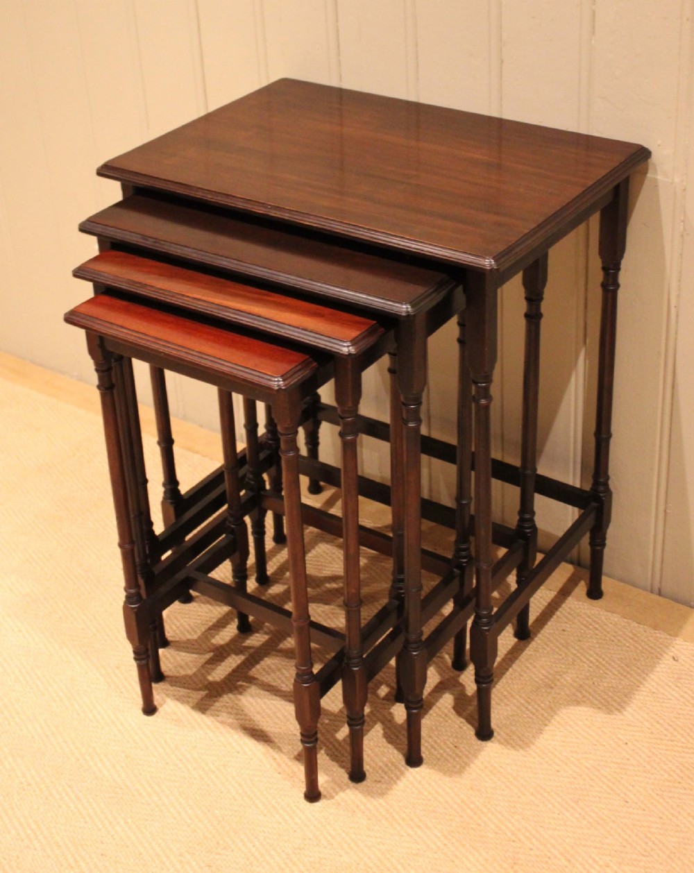 A set of four graduated mahogany nesting tables featuring rectangular tops with moulded edges, slender turned legs, and connecting stretchers. View III