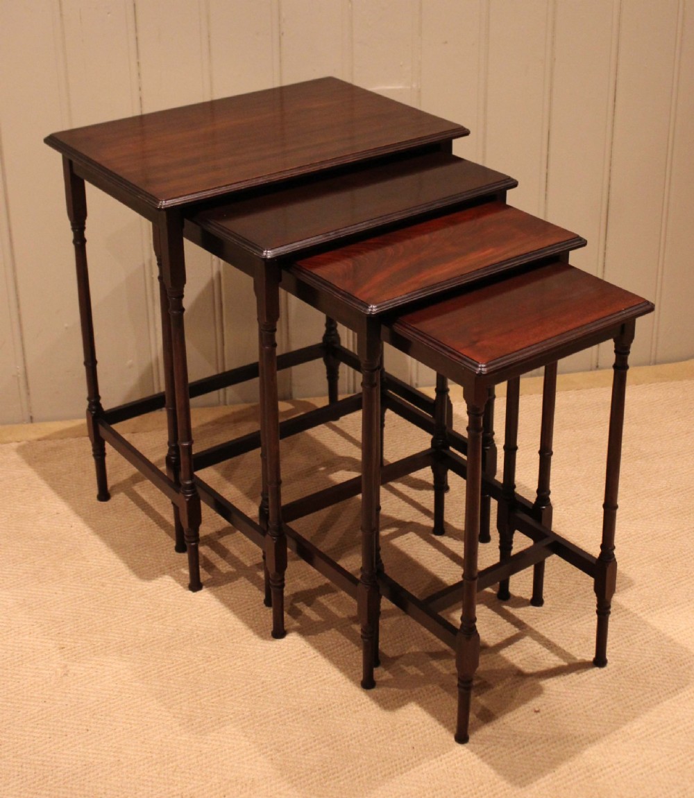 A set of four graduated mahogany nesting tables featuring rectangular tops with moulded edges, slender turned legs, and connecting stretchers. View V