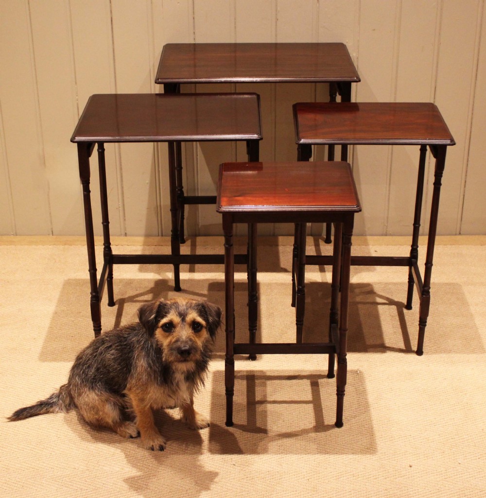 A set of four graduated mahogany nesting tables featuring rectangular tops with moulded edges, slender turned legs, and connecting stretchers. View VII