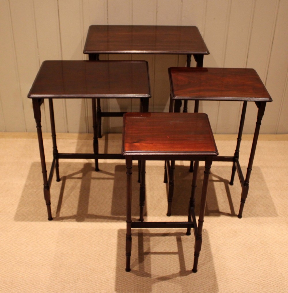 A set of four graduated mahogany nesting tables featuring rectangular tops with moulded edges, slender turned legs, and connecting stretchers. View IX