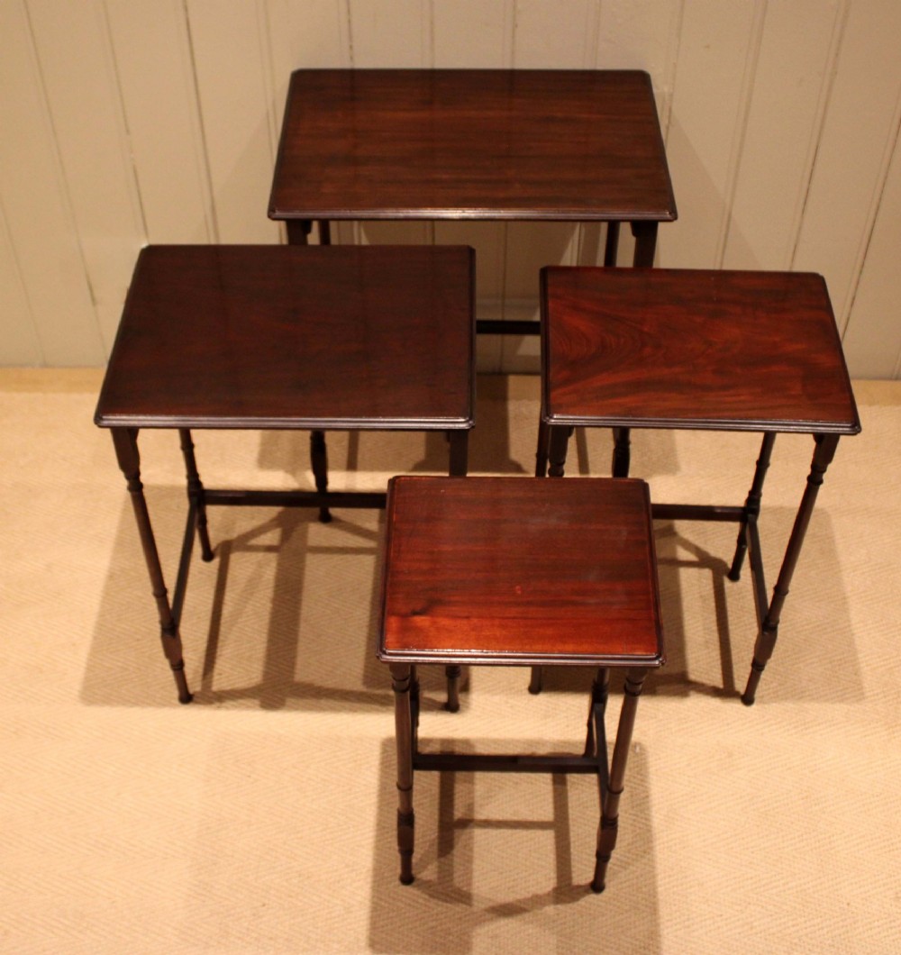A set of four graduated mahogany nesting tables featuring rectangular tops with moulded edges, slender turned legs, and connecting stretchers. View XI