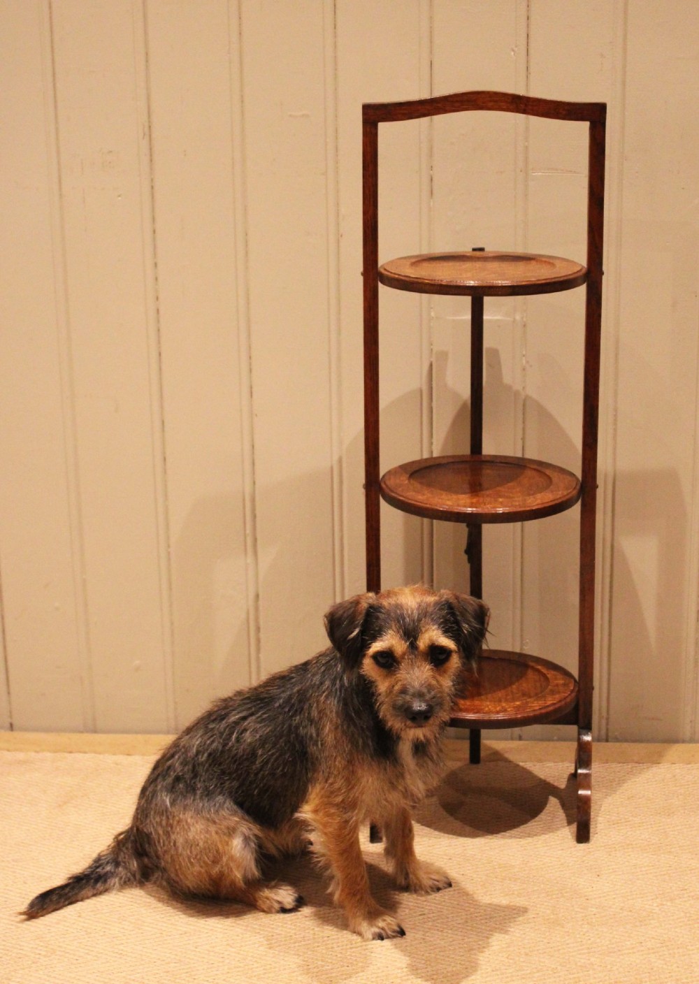 An Edwardian oak three-tier folding cake stand featuring circular recessed shelves and an arched carrying handle. View VIII