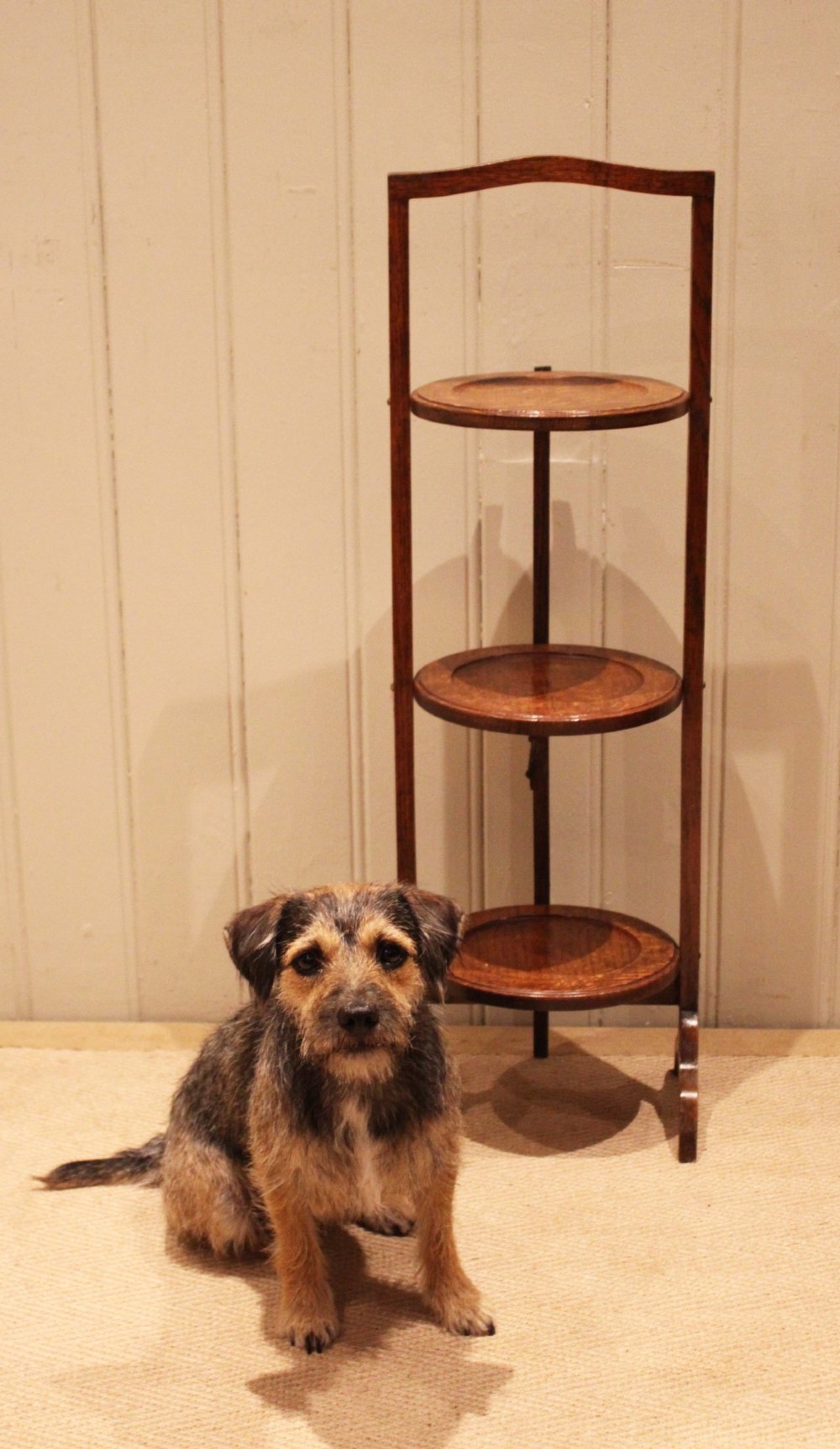 An Edwardian oak three-tier folding cake stand featuring circular recessed shelves and an arched carrying handle. View XI