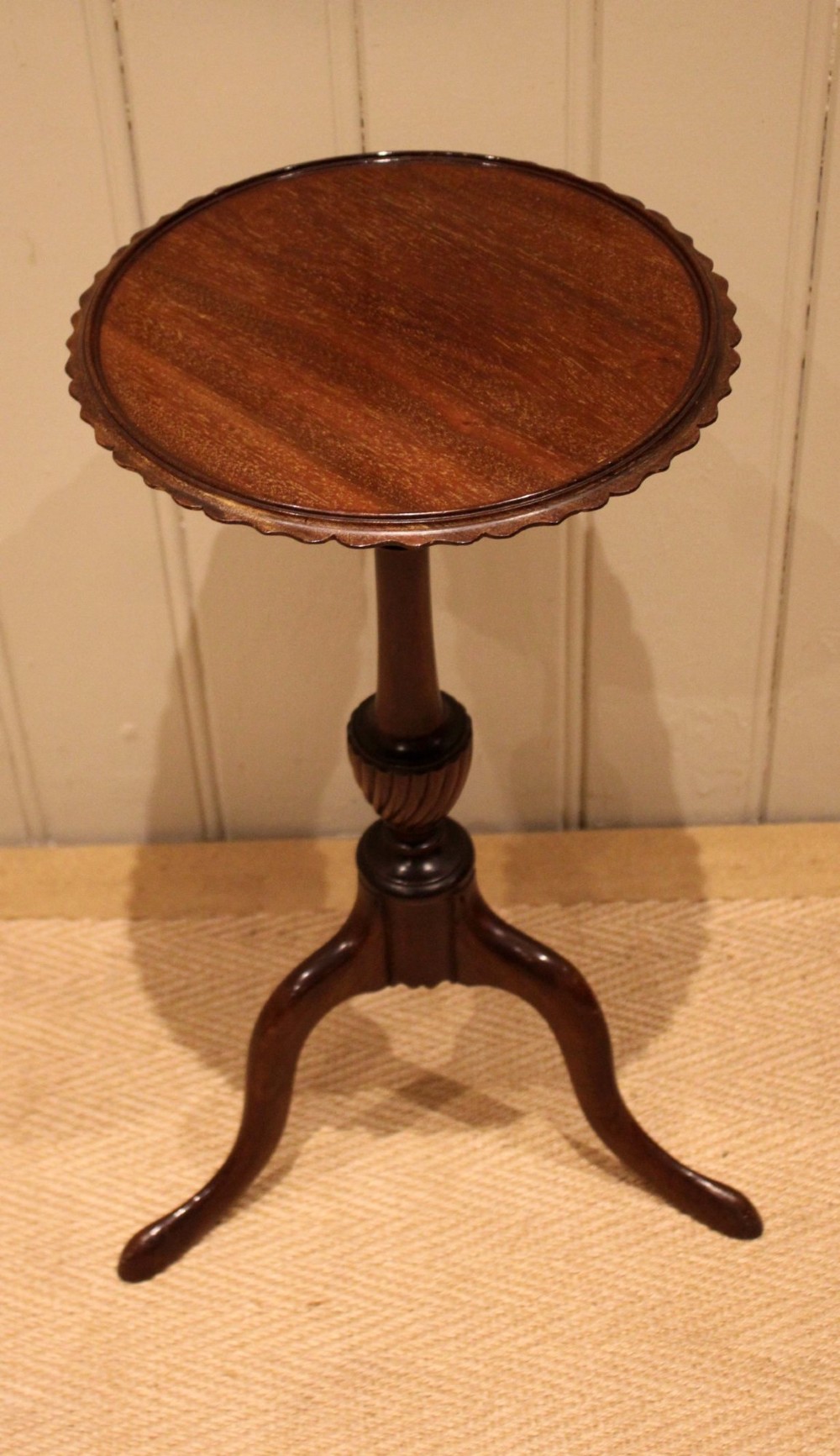 An Edwardian mahogany wine table featuring a scalloped piecrust circular top, a turned central stem, and three splayed tripod legs. View II