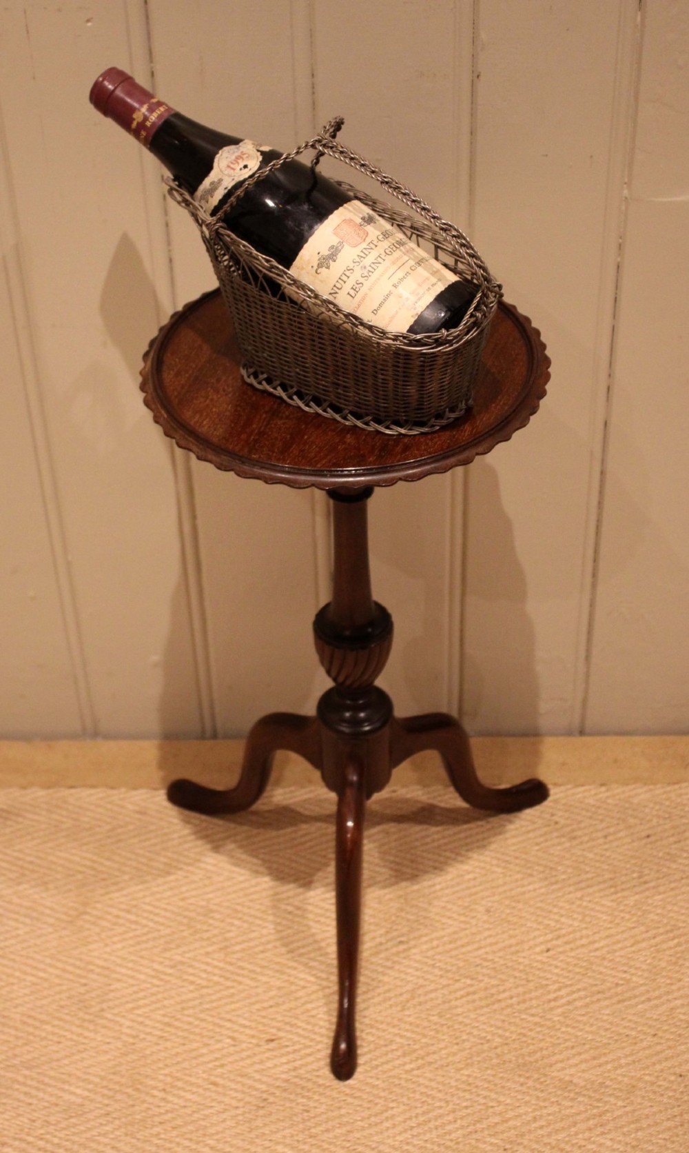 An Edwardian mahogany wine table featuring a scalloped piecrust circular top, a turned central stem, and three splayed tripod legs. View III