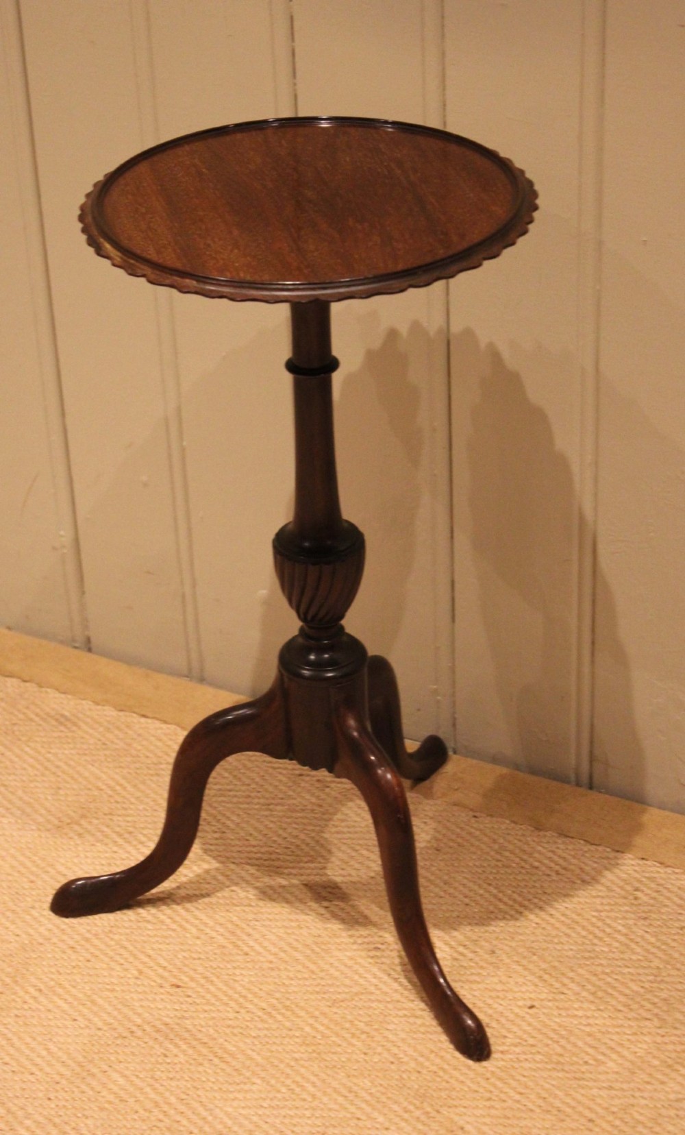 An Edwardian mahogany wine table featuring a scalloped piecrust circular top, a turned central stem, and three splayed tripod legs. View V