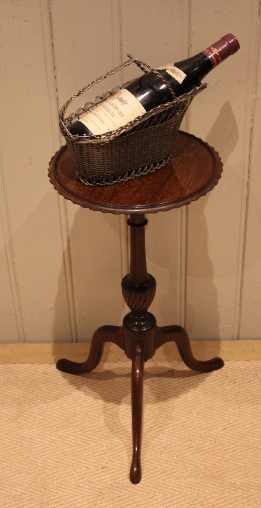 An Edwardian mahogany wine table featuring a scalloped piecrust circular top, a turned central stem, and three splayed tripod legs. View VI