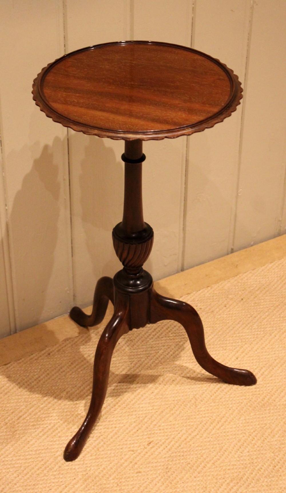 An Edwardian mahogany wine table featuring a scalloped piecrust circular top, a turned central stem, and three splayed tripod legs. View VII