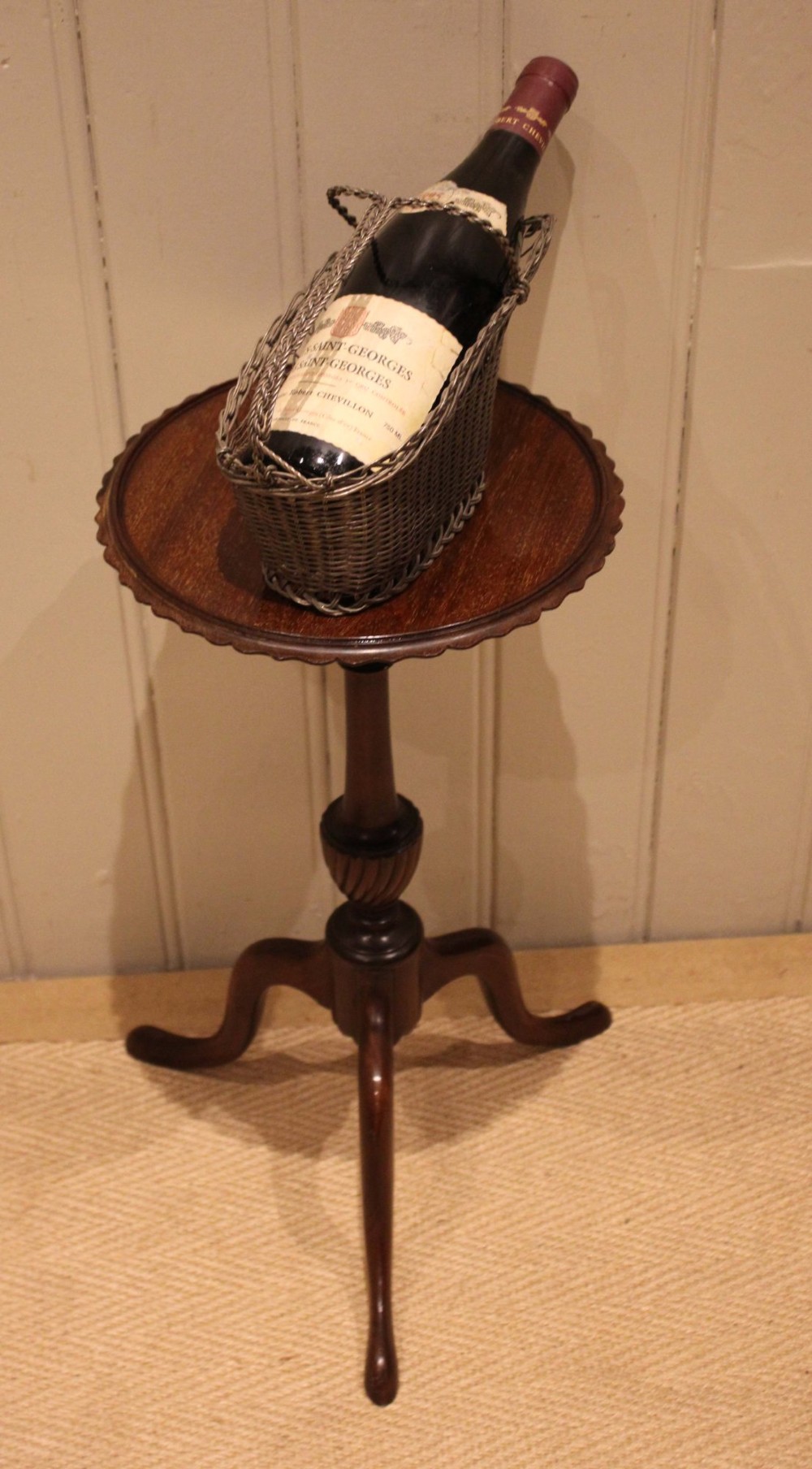 An Edwardian mahogany wine table featuring a scalloped piecrust circular top, a turned central stem, and three splayed tripod legs. View VIII
