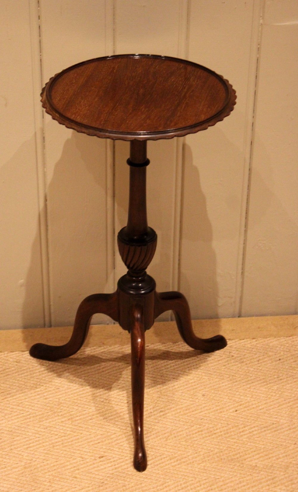 An Edwardian mahogany wine table featuring a scalloped piecrust circular top, a turned central stem, and three splayed tripod legs. View IX