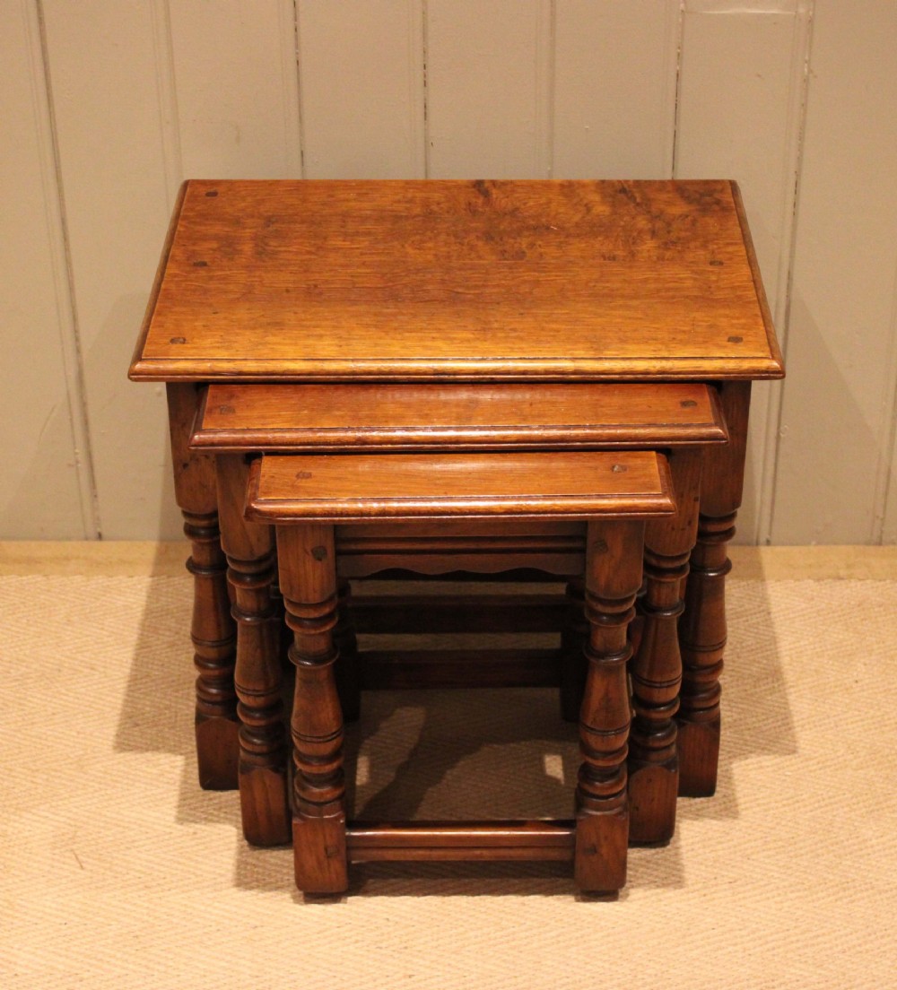 A set of three graduating solid oak nesting tables featuring turned legs, box stretchers, and rectangular molded tops. View III