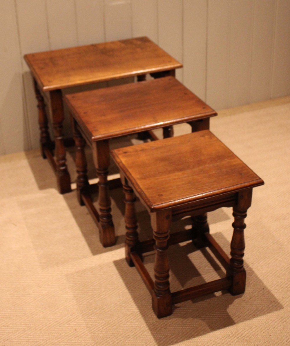 A set of three graduating solid oak nesting tables featuring turned legs, box stretchers, and rectangular molded tops. View IV