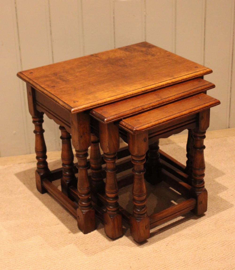 A set of three graduating solid oak nesting tables featuring turned legs, box stretchers, and rectangular molded tops. View V