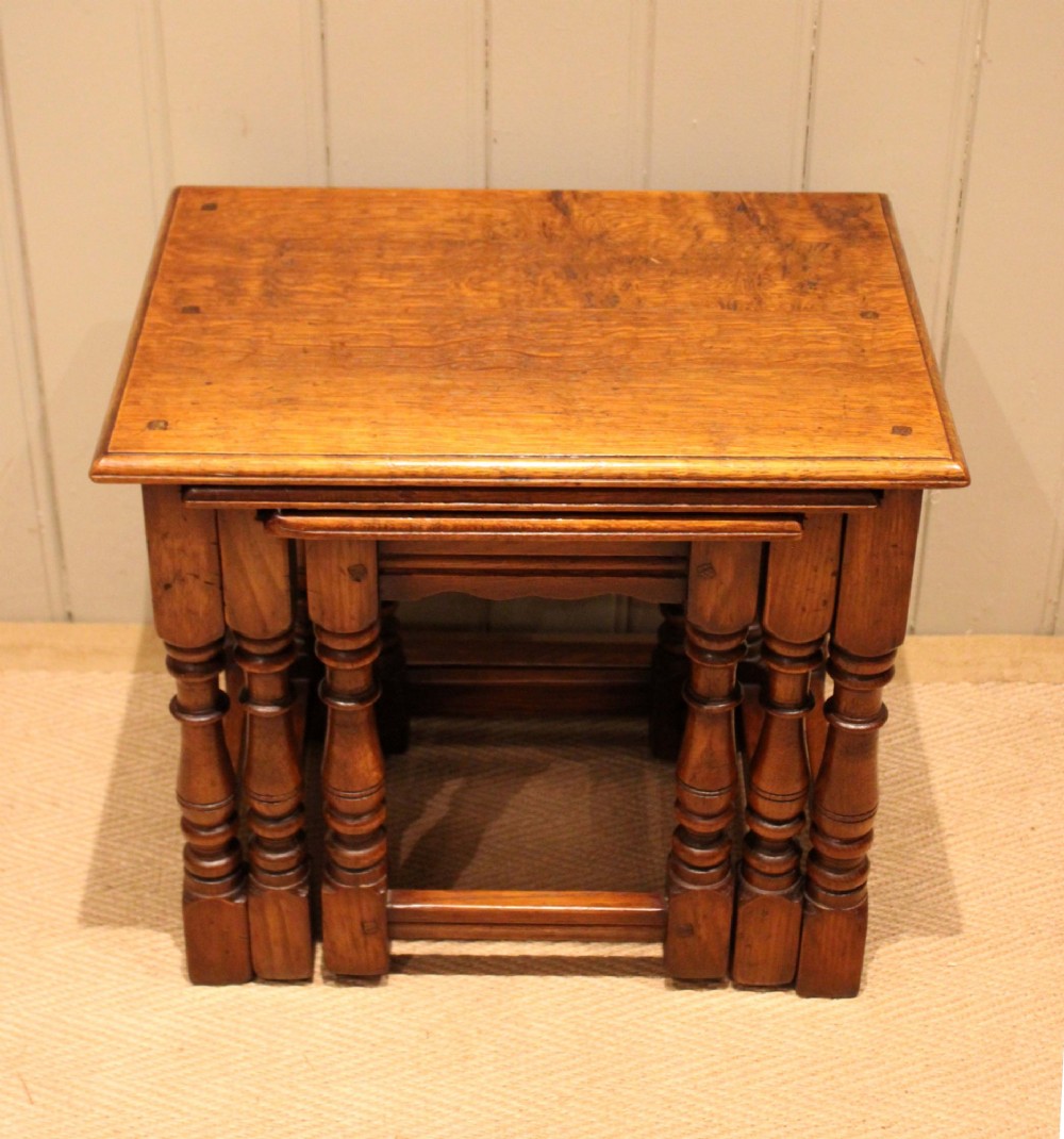 A set of three graduating solid oak nesting tables featuring turned legs, box stretchers, and rectangular molded tops. View VII