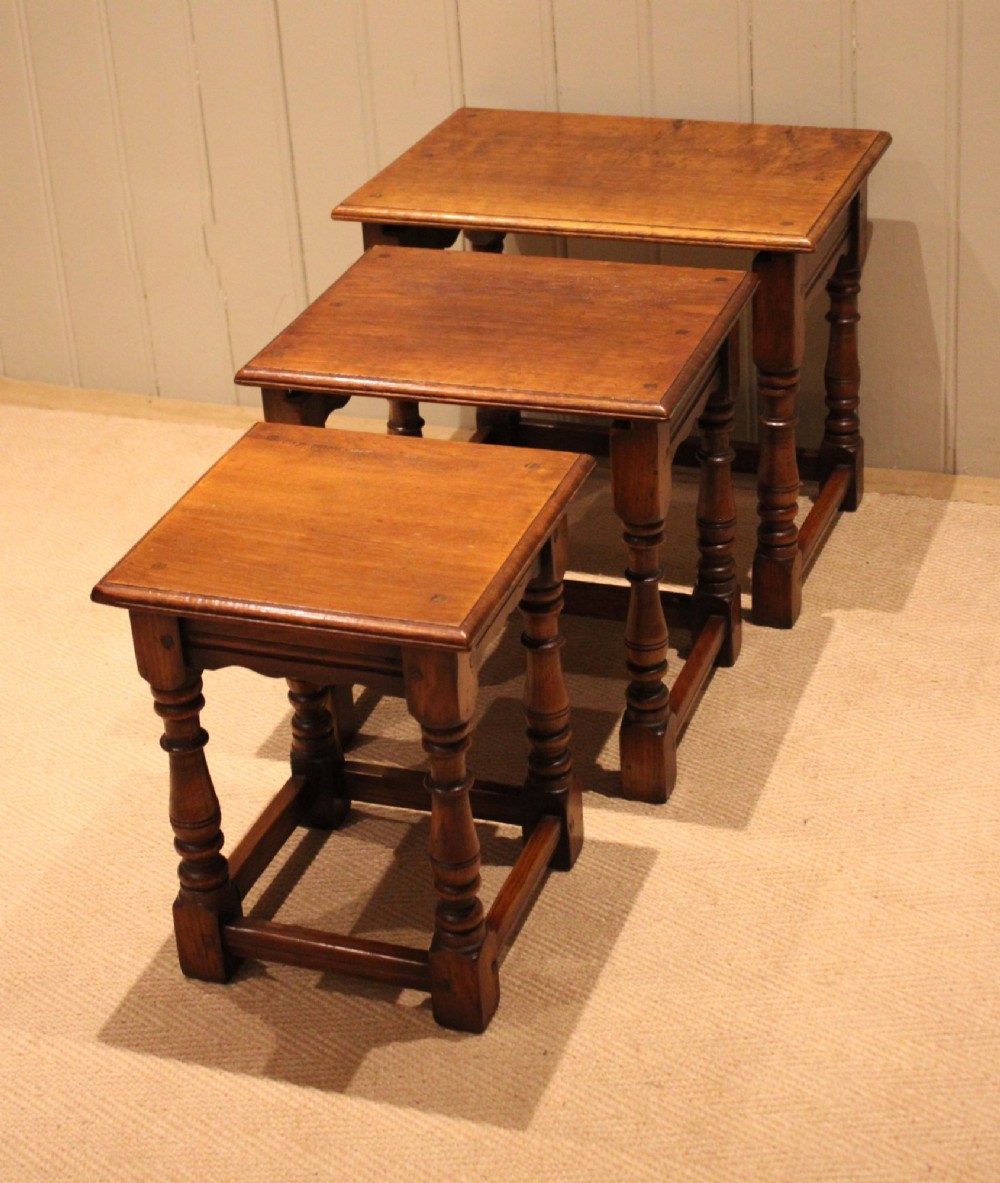A set of three graduating solid oak nesting tables featuring turned legs, box stretchers, and rectangular molded tops. View IX