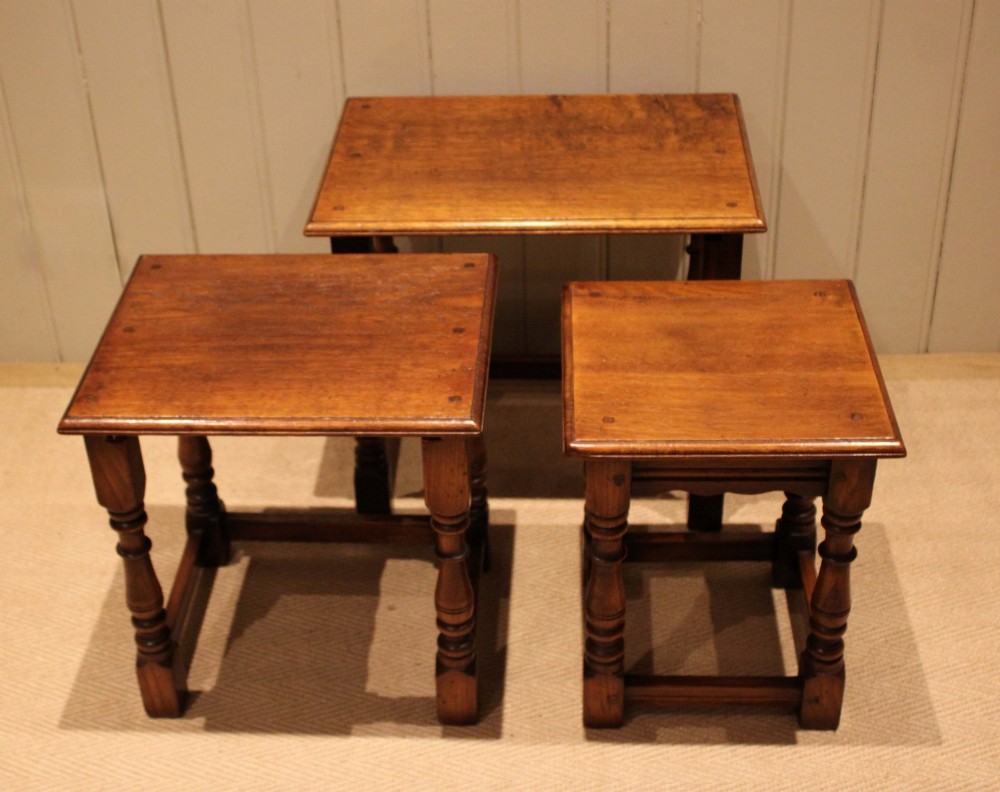 A set of three graduating solid oak nesting tables featuring turned legs, box stretchers, and rectangular molded tops. View X