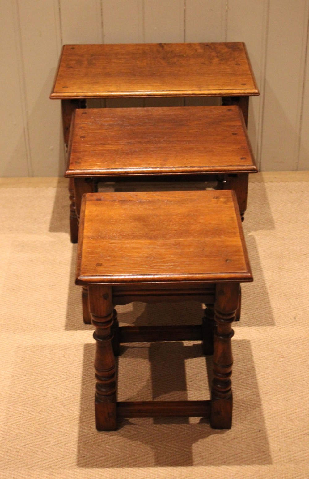 A set of three graduating solid oak nesting tables featuring turned legs, box stretchers, and rectangular molded tops. View XI