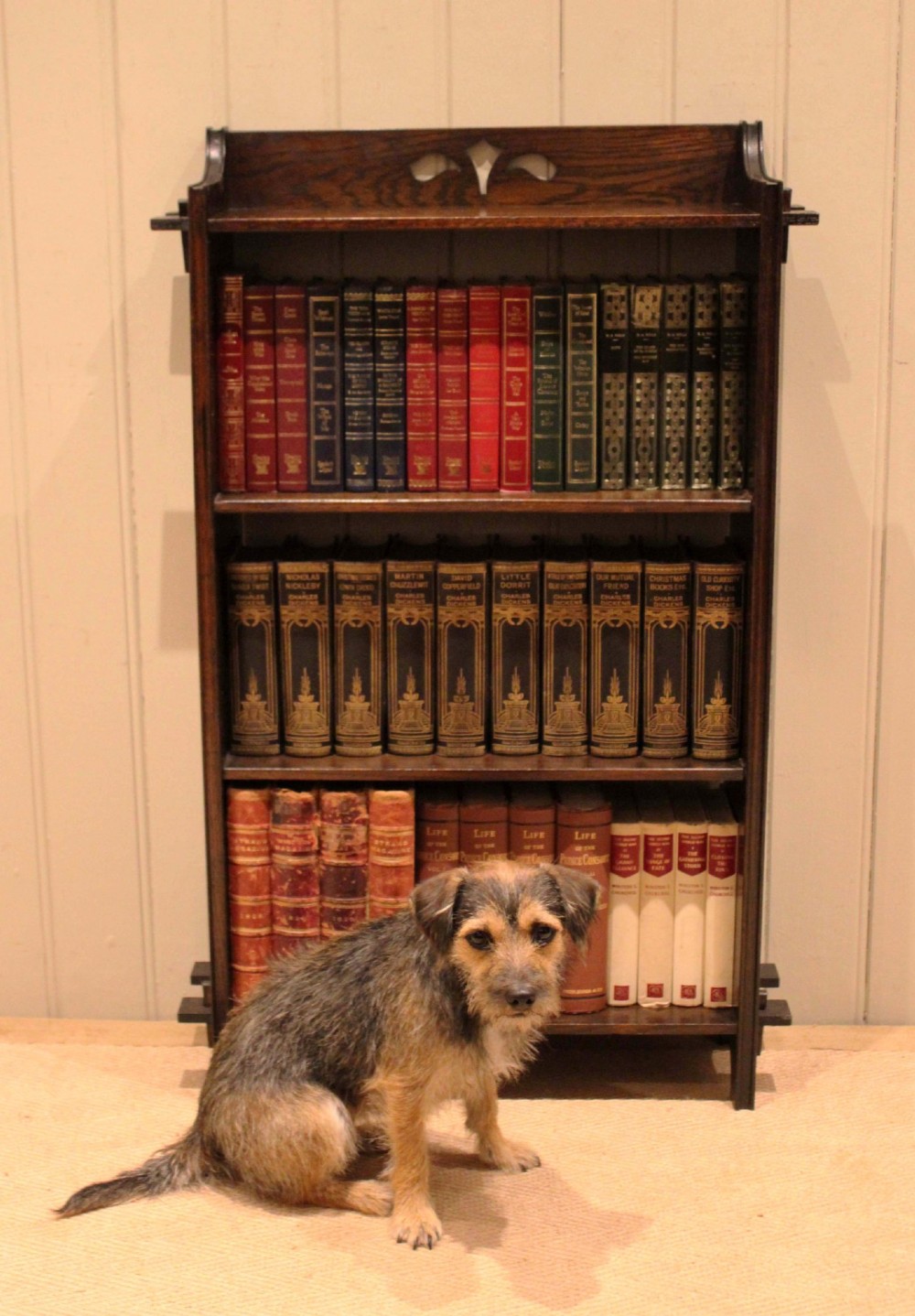 A dark oak open bookcase featuring three shelves, protruding pegged side joints, and a shaped top gallery with a pierced motif. View XII