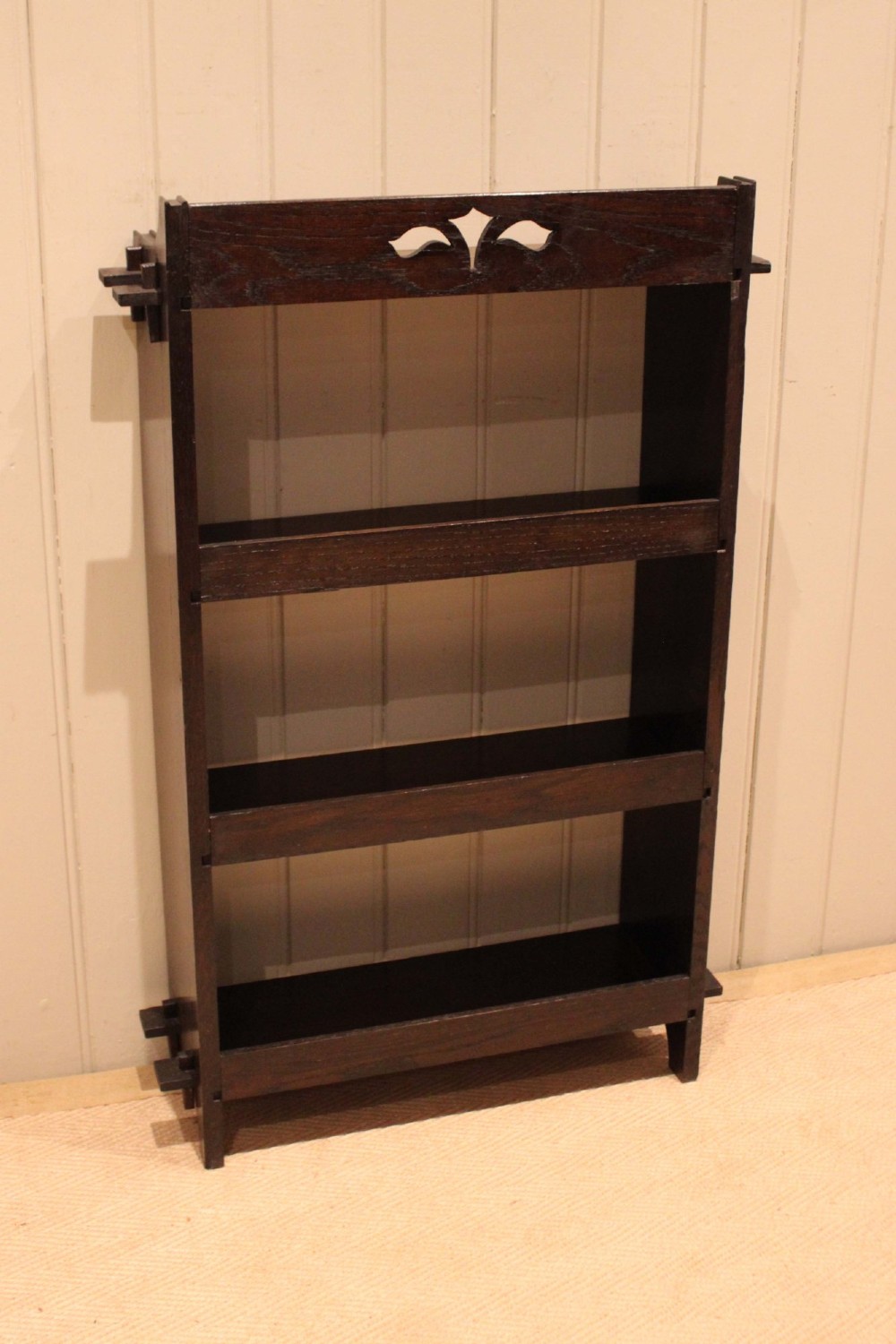 A dark oak open bookcase featuring three shelves, protruding pegged side joints, and a shaped top gallery with a pierced motif. View XIII