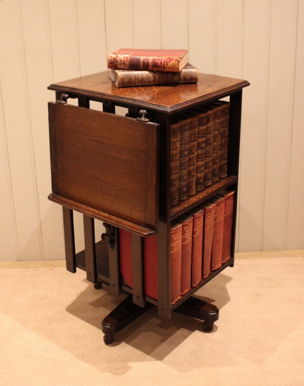 A dark oak revolving bookcase featuring vertical slatted sides, an adjustable reading lectern, and a four-point base on castors. View III