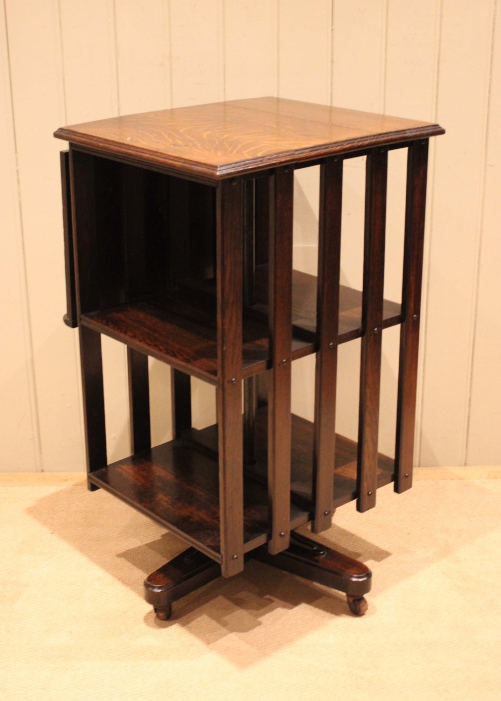 A dark oak revolving bookcase featuring vertical slatted sides, an adjustable reading lectern, and a four-point base on castors. View IV